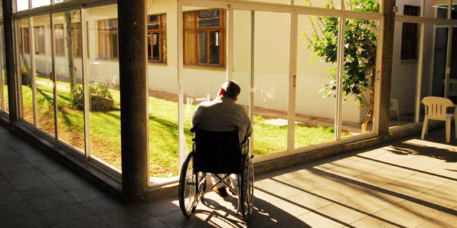Hombre en silla de ruedas observando un patio interior
